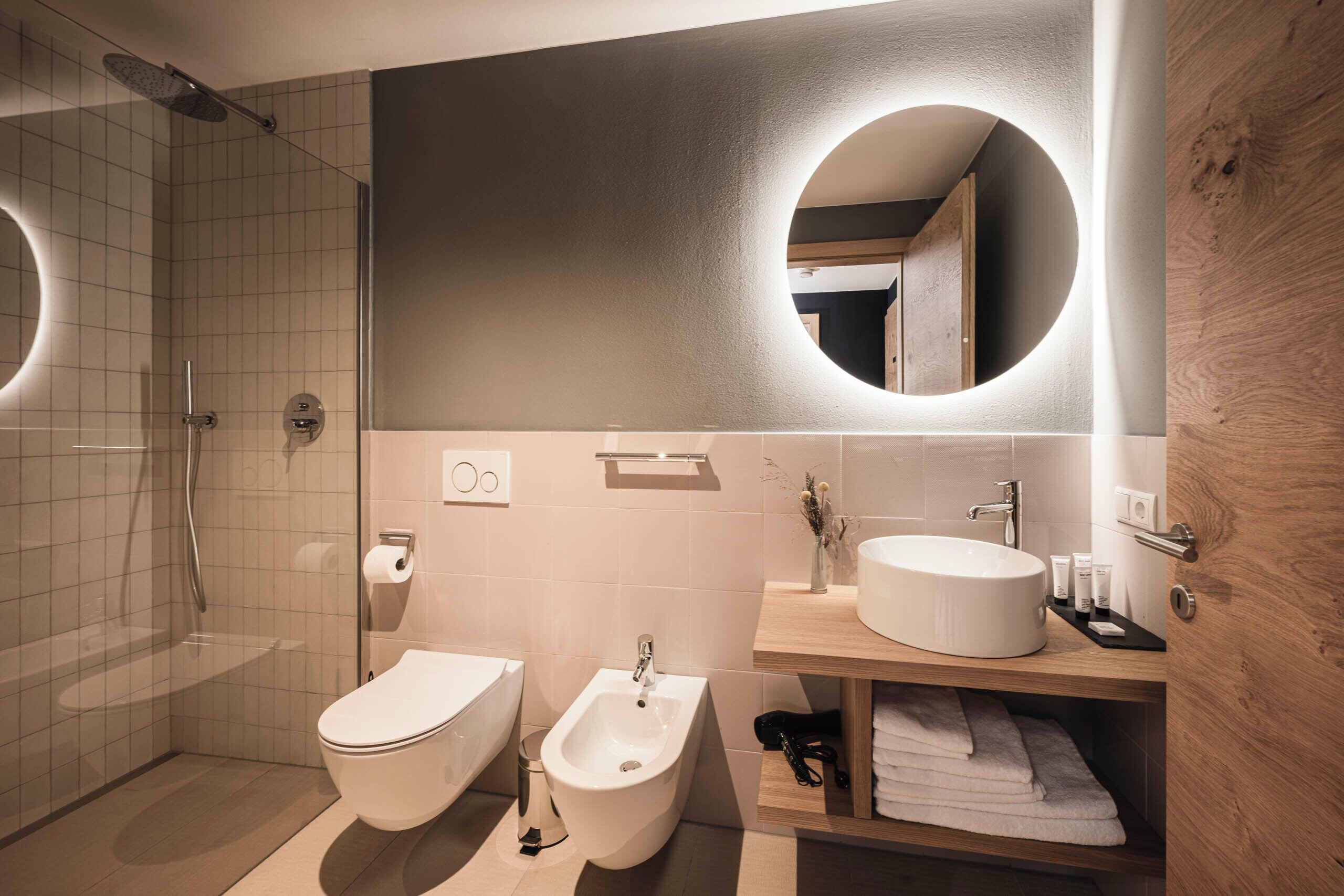 A modern bathroom with a shower, toilet, bidet, and sink.