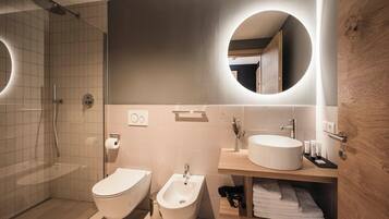 A modern bathroom with a shower, toilet, bidet, and sink.