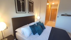 A hotel room with a bed, a nightstand, a lamp, and two framed pictures on the wall. - La Envía - Beautiful apartment with terrace, swimming pool, luminous (La Envía)