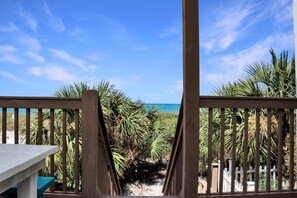 A wooden deck with a view of the ocean and palm trees. - Sunset Treasures (Port St. Joe)