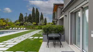Un patio moderno al aire libre con piscina, un sendero de piedra y una zona de estar con mesa y sillas.