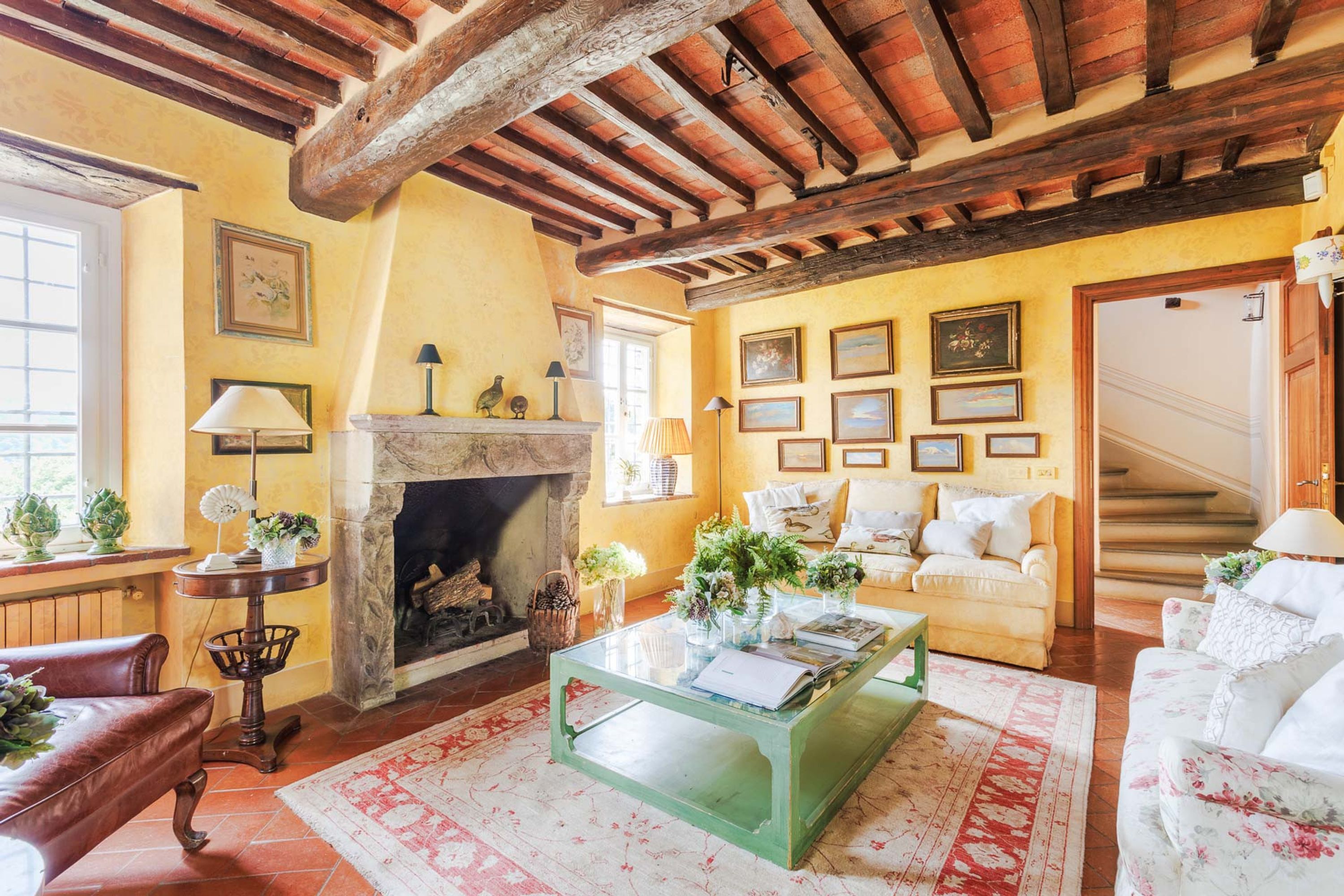 A cozy living room with a fireplace, a green coffee table, and a staircase leading to another level.