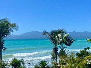 A beach with turquoise water, palm trees, and mountains in the background. - Sea, boat and mountain views, beach just around the corner! (Le Gosier)