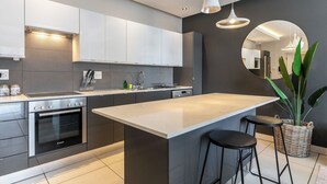 Une cuisine moderne dotée d’un îlot central, d’appareils électroménagers en acier inoxydable et d’un grand miroir.