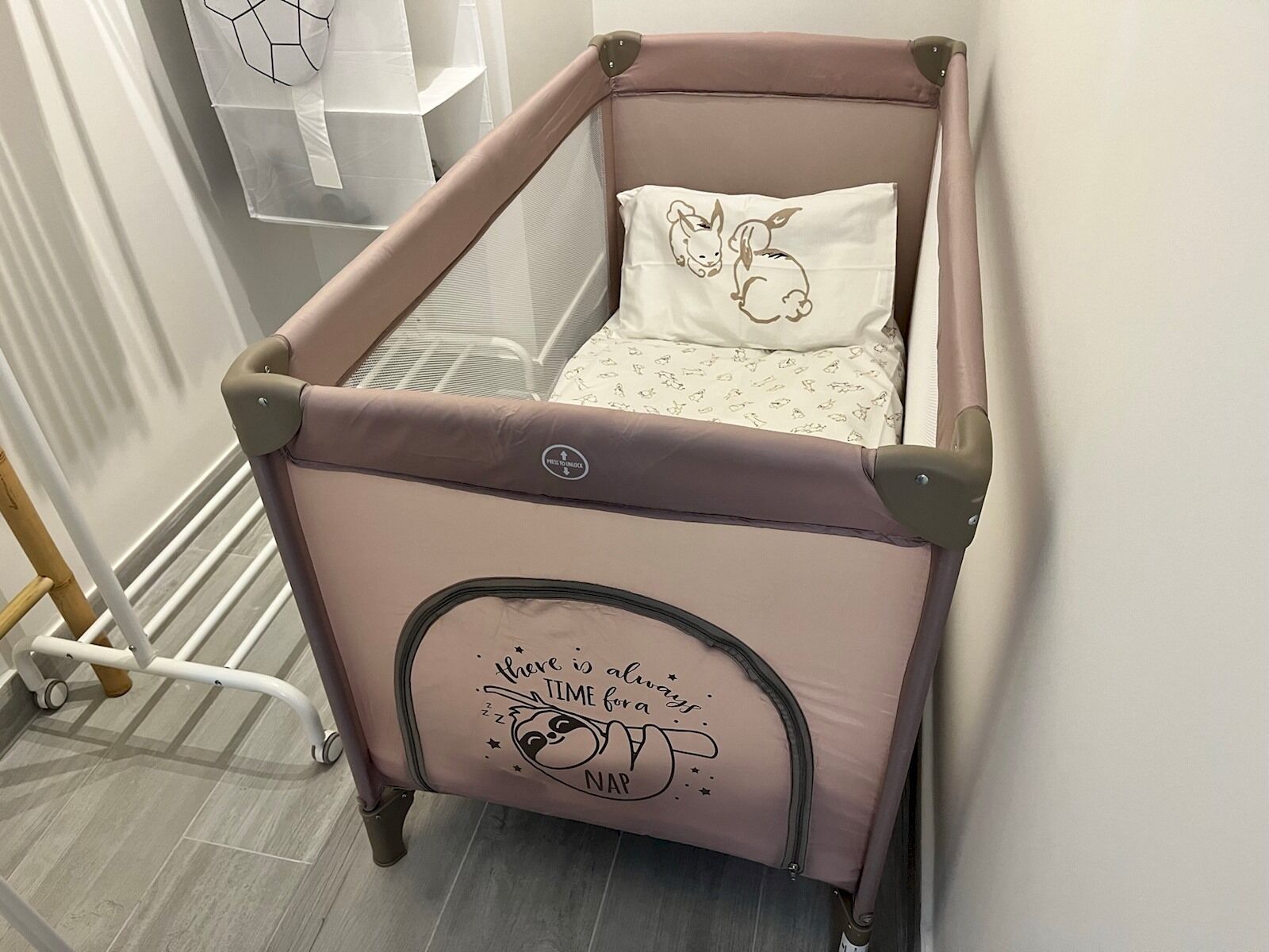 A pink baby stroller with a cushion featuring a bunny design and a message about nap time.