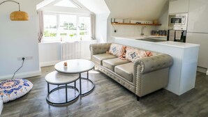A modern loft apartment with a kitchen, a sofa, a round coffee table, and a dining area. - The Gatekeepers Cottage - Skerry Vore (Llandudno Junction)