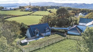 A rural property with a fenced yard, a small building with a sloped roof, and a large tree. - The Gatekeepers Cottage - Skerry Vore (Llandudno Junction)