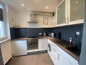 A modern kitchen with white cabinetry, a built-in oven, microwave, and dishwasher.