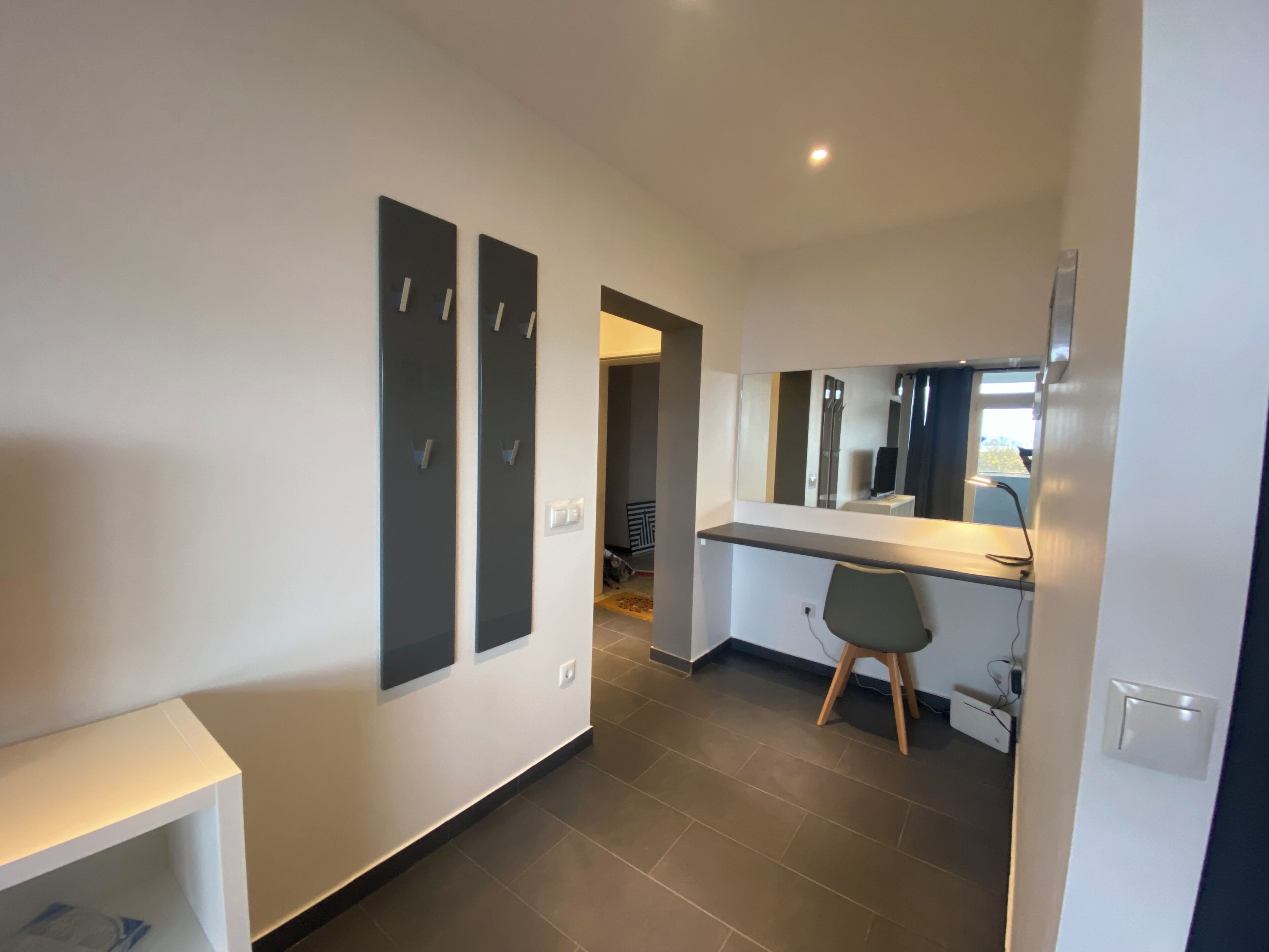 A modern hotel room with a large mirror, a desk, and a chair.