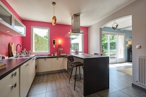 A modern kitchen with a central island, a large window, and a view of the outdoors.