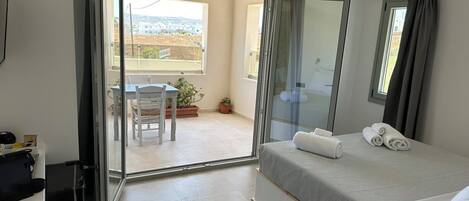 A hotel room with a bed, a desk, a chair, and a balcony with a view.
