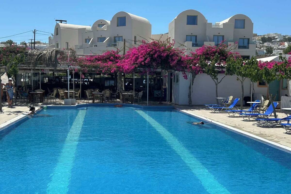 A swimming pool with lounge chairs and a covered seating area.