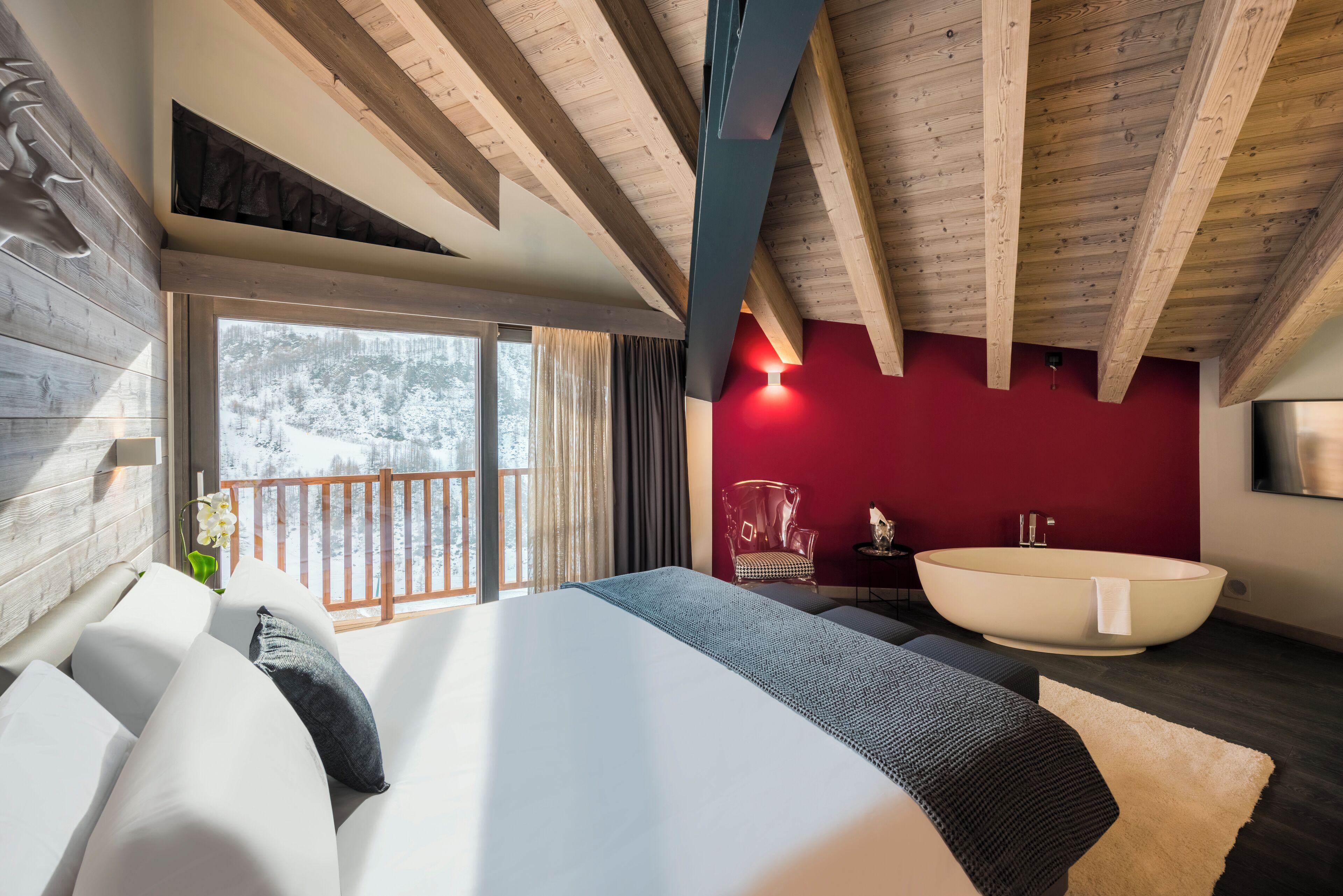 Un dormitorio moderno con una cama grande, una bañera y vistas a un paisaje nevado.