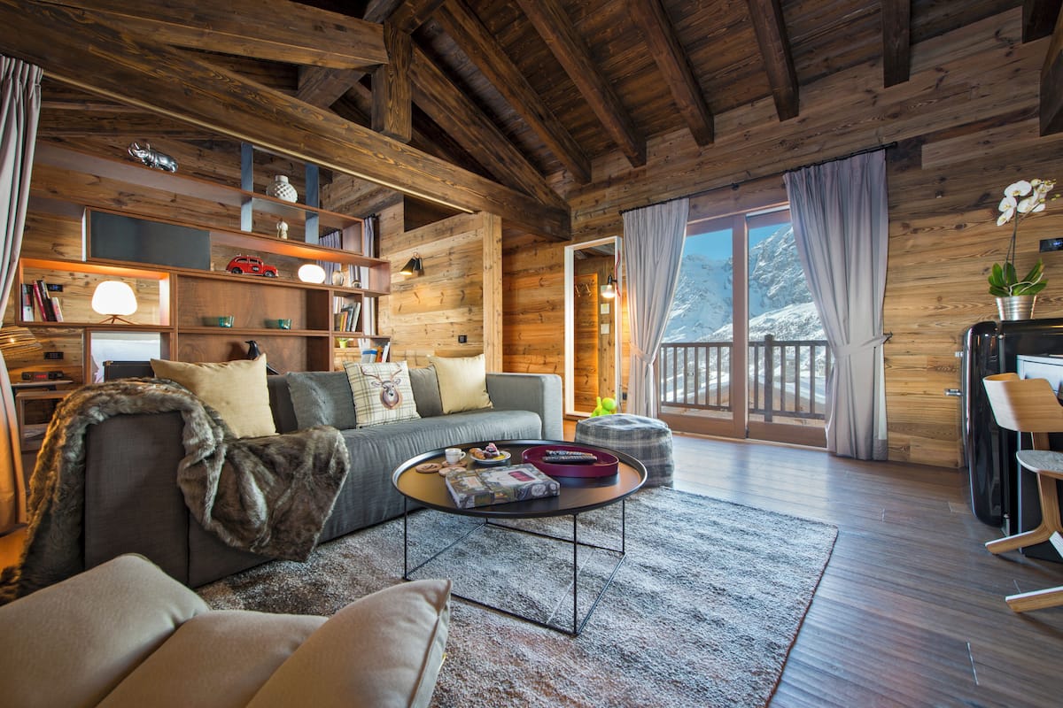 A cozy log cabin interior with a sofa, coffee table, and wooden shelves.