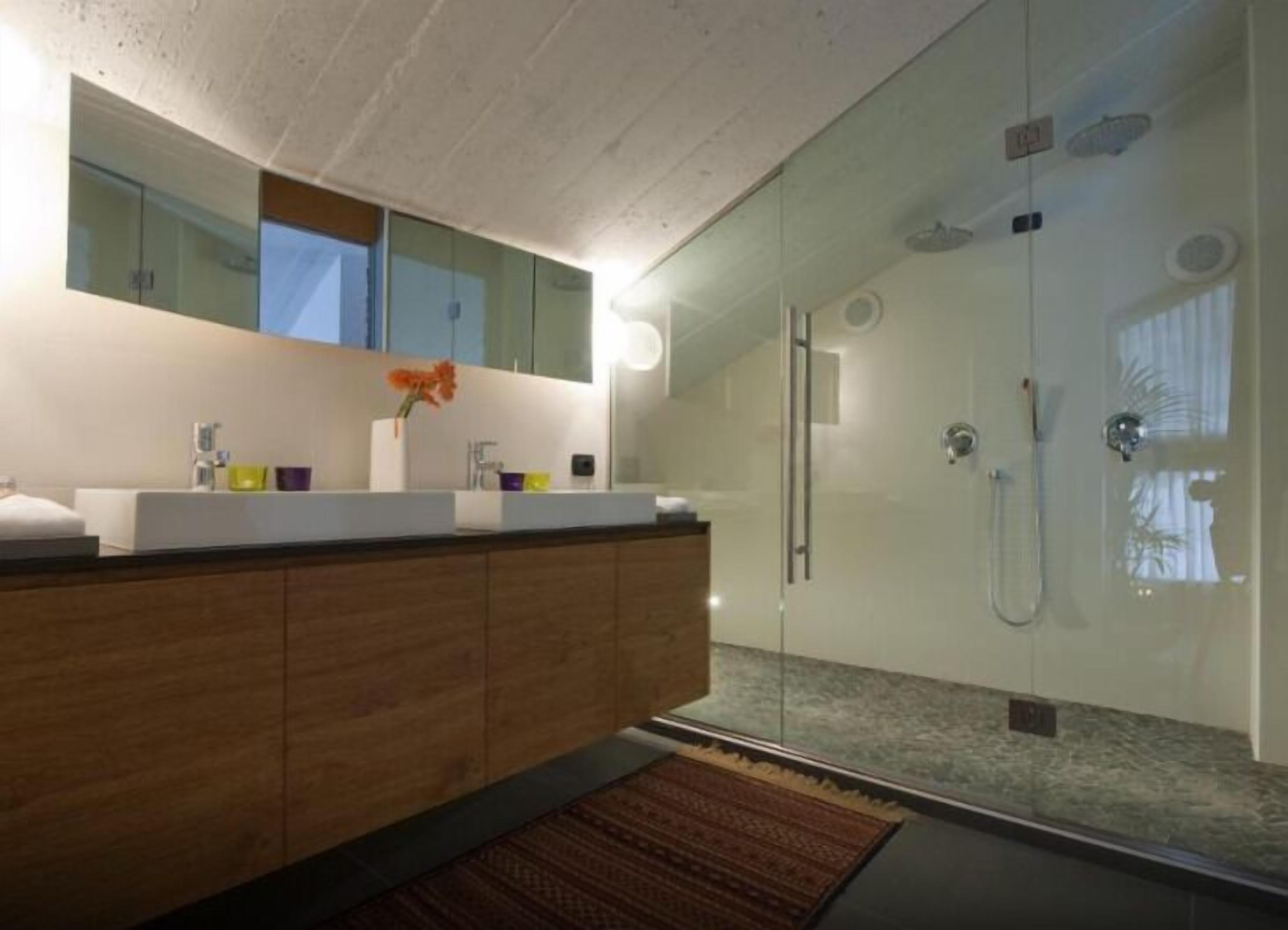 A modern bathroom with a glass-enclosed shower, a wooden vanity, and a large mirror above the sink.
