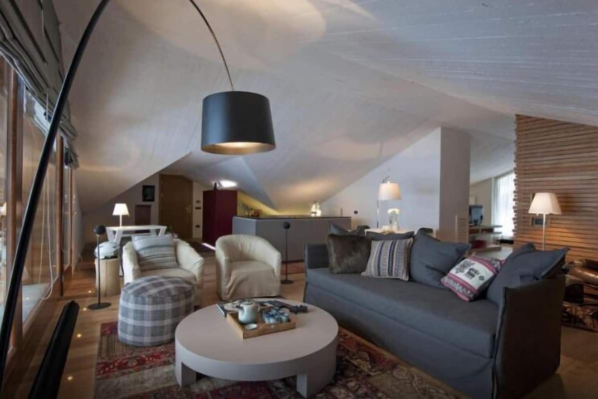 A modern loft-style living room with a high ceiling, a round coffee table, a sofa, and a dining area in the background.