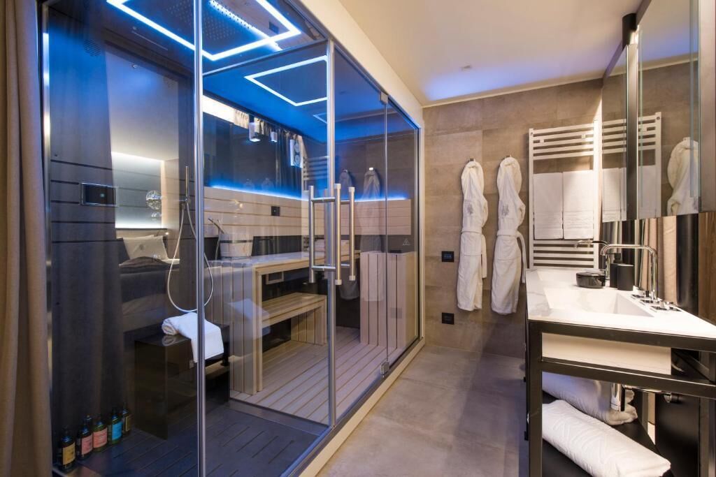 A modern bathroom with a glass-enclosed shower, a vanity with a mirror, and a towel rack.