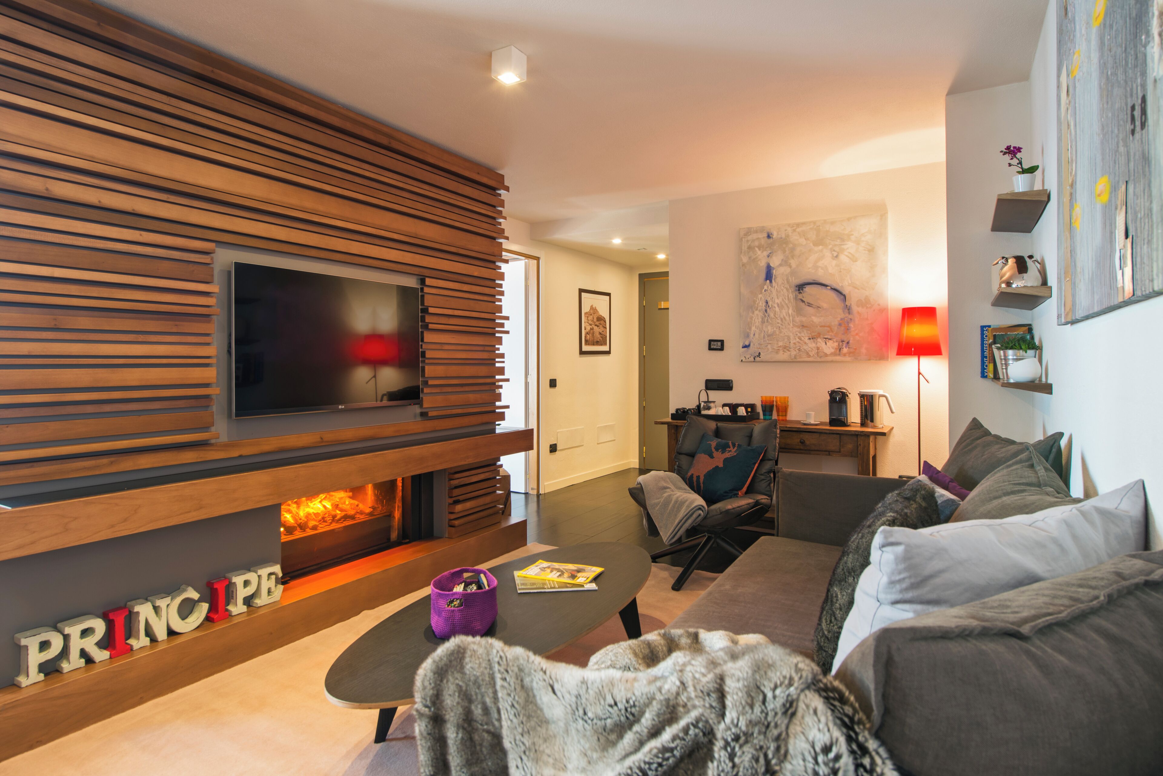 A modern living room with a fireplace, a flat-screen TV, and a sofa.