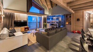 Een moderne woonkamer met een grote televisie, een bank en een eethoek met stoelen.