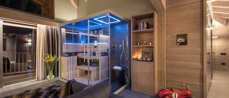 A modern living room with a glass-enclosed sauna, a red toy car, and wooden walls.