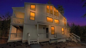 A two-story wooden house with a balcony on the upper floor, a front porch, and a staircase leading to the entrance. - Kingswood Village Escape – For 4 (Kings Beach)