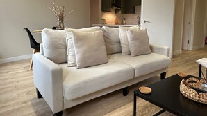 Un salon moderne avec un canapé de couleur claire, une table basse noire et un panier en osier.