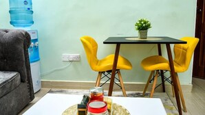 A small living area with a sofa, two yellow chairs, a table with a potted plant, and a water dispenser. - Vimally Suites Naivasha (Naivasha)