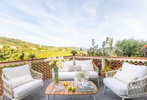 A terrace with wicker furniture, a coffee table, and a vase of flowers. - The Sea Air Villa in Massarosa (Massarosa)