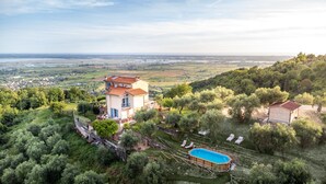 Ein zweistöckiges Haus mit Schwimmbad, umgeben von üppiger Vegetation und einem schönen Ausblick über ein Tal.