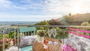 En balkon med fletmøbler, en vase med blomster og to glas champagne.