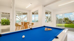 Une table de billard recouverte d’un drap bleu, entourée de quatre chaises, et une bille blanche.