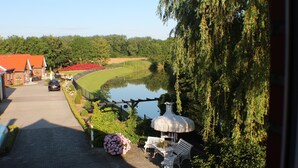 A pathway leading to a pond with benches and a gazebo, surrounded by greenery and a building with a red roof. - Apartment 'Adlerhorst' with Shared Terrace, Wi-Fi and Air Conditioning (Wangerland)