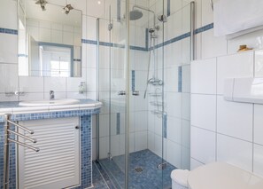 Un bagno moderno con cabina doccia in vetro, un lavabo con piano in piastrelle blu e un water bianco.