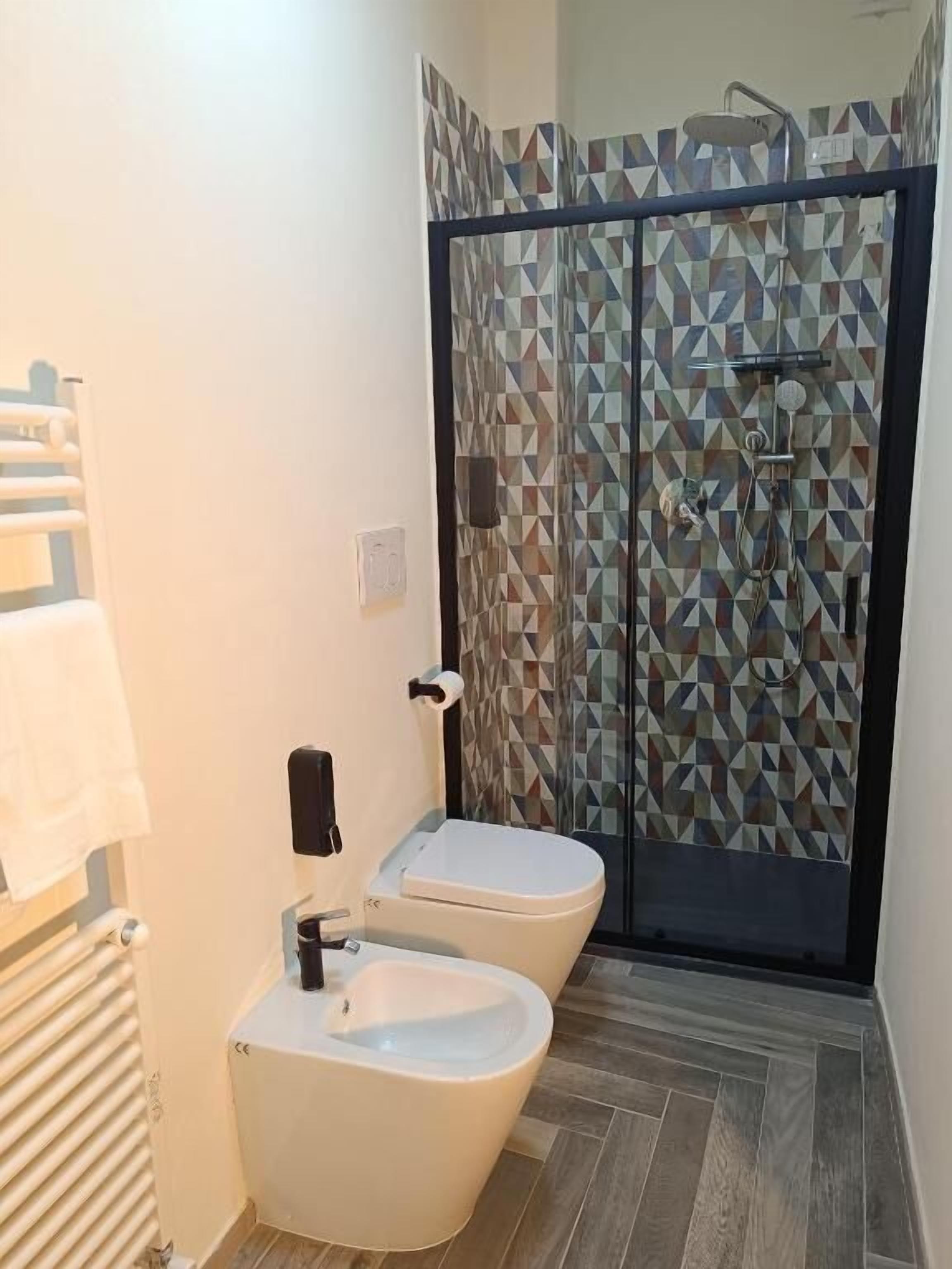 Une salle de bain équipée d’une douche, de toilettes, d’un bidet et d’un porte-serviettes.