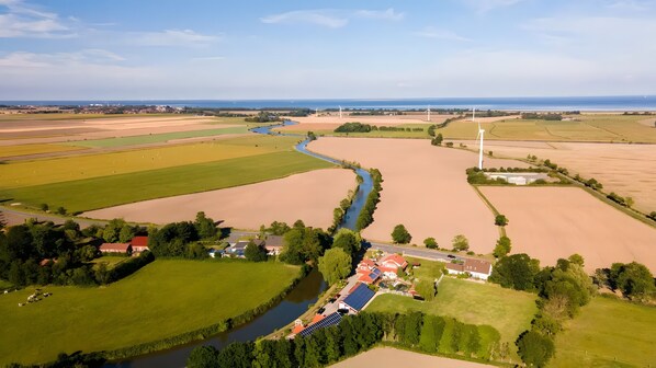 An aerial view of a rural landscape with fields, a river, wind turbines, and solar panels.