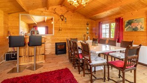 Ein Holzinterieur mit Esstisch, Stühlen, Kamin und einer Kandelaber.