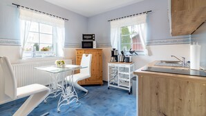 Eine kleine Küche mit Mikrowelle, Herd und Spüle, Holzausstattung und einem Essbereich mit weißem Stuhl und Tisch.