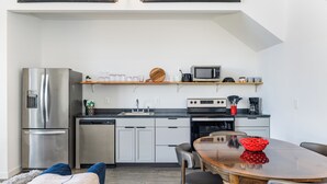Eine moderne Küche mit Edelstahlgeräten, einem Holzessttisch und einer gemütlichen Sitzecke.