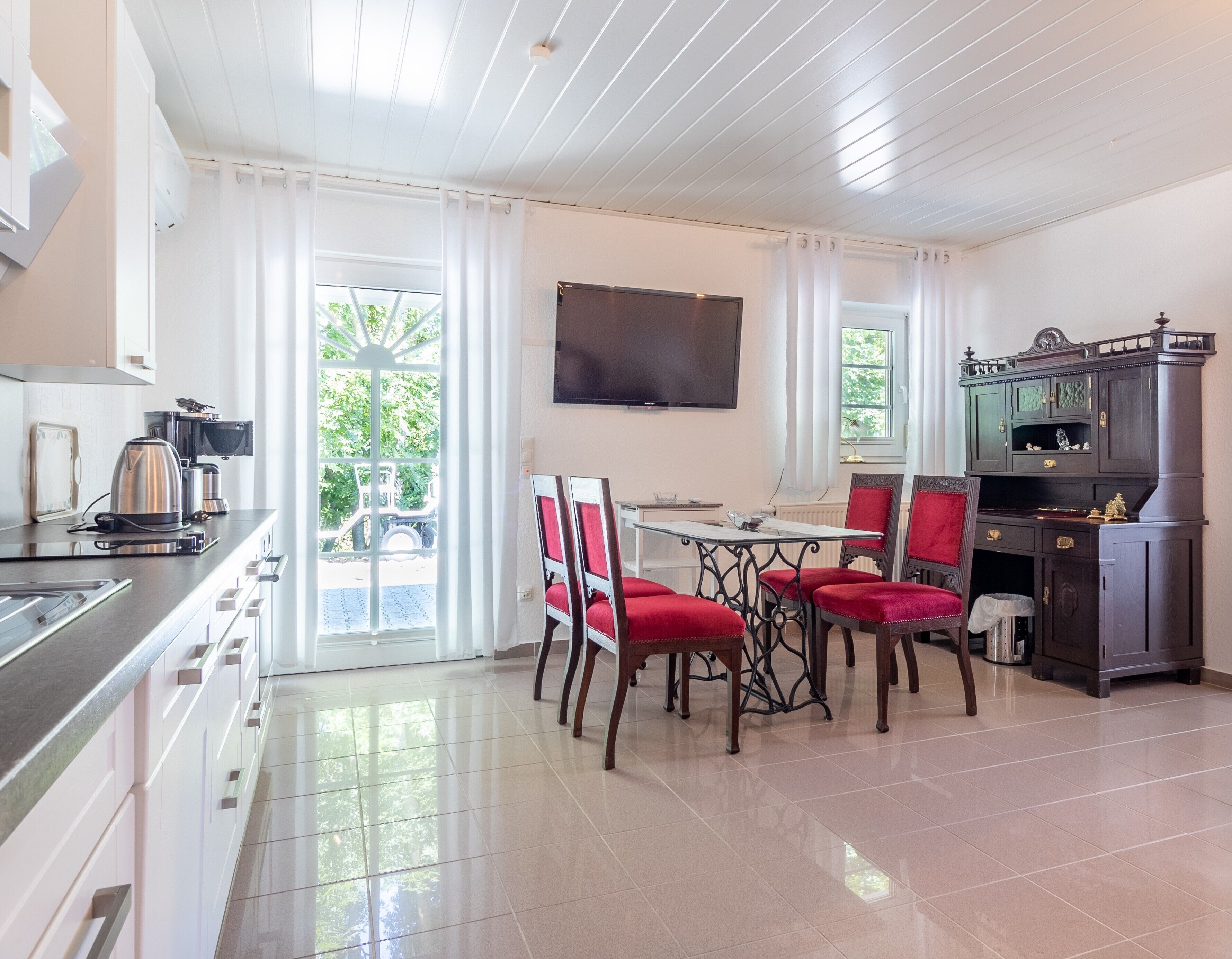 Una cocina moderna con comedor, televisor de pantalla plana y vistas al exterior.