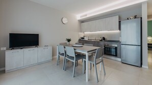 Una cocina moderna con comedor, electrodomésticos integrados y un televisor de pantalla plana.