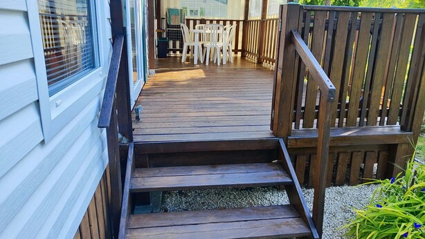 A wooden deck leading to a covered patio area with a table and chairs. - Mobil home Le Duo Tranquille (Souvigné)