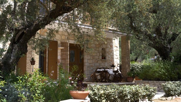 A stone building with a covered patio, surrounded by olive trees and potted plants. - Rosemary Cottage, Lioriza Houses Zakynthos (Zakynthos)