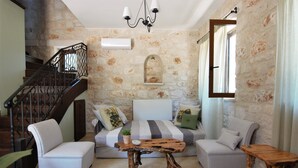A living room with a stone wall, a wooden staircase, and a sofa set. - Rosemary Cottage, Lioriza Houses Zakynthos (Zakynthos)