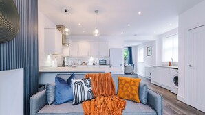 A modern kitchen with white cabinets, a central island, and a built-in oven. - 3BR House w/ Parking, Free Wifi, and Discounts! (Droylsden)