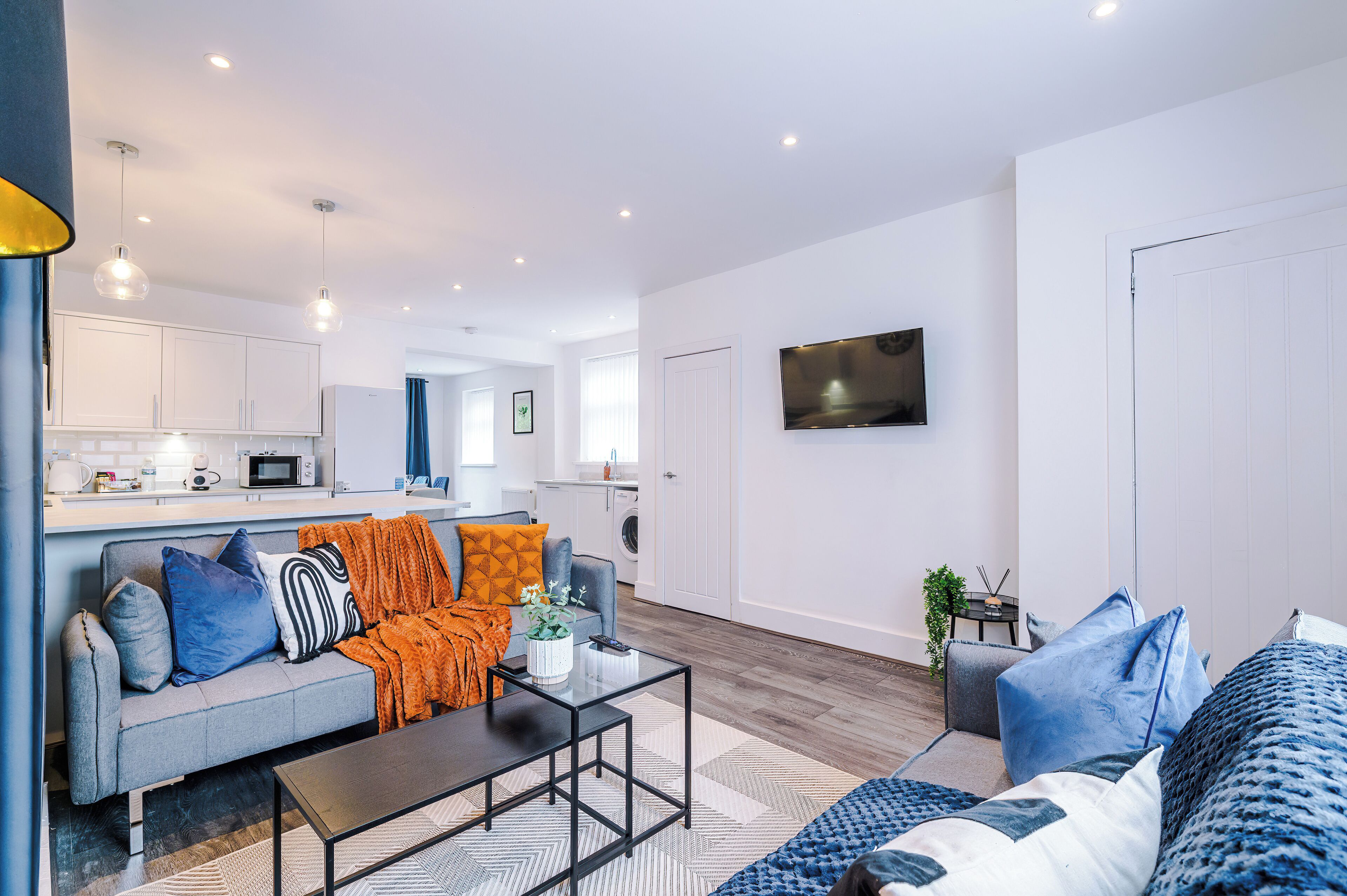 Ein modernes Wohnzimmer mit einer Couch, einem Couchtisch und einem an der Wand montierten Fernseher.