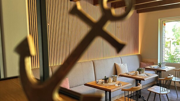 Un restaurant chaleureux avec un plafond en bois, un canapé et des tables dressées pour le repas.