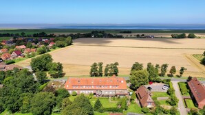 Une vue aérienne d’un quartier résidentiel avec des maisons, un grand champ ouvert et un bâtiment doté d’un toit rouge.