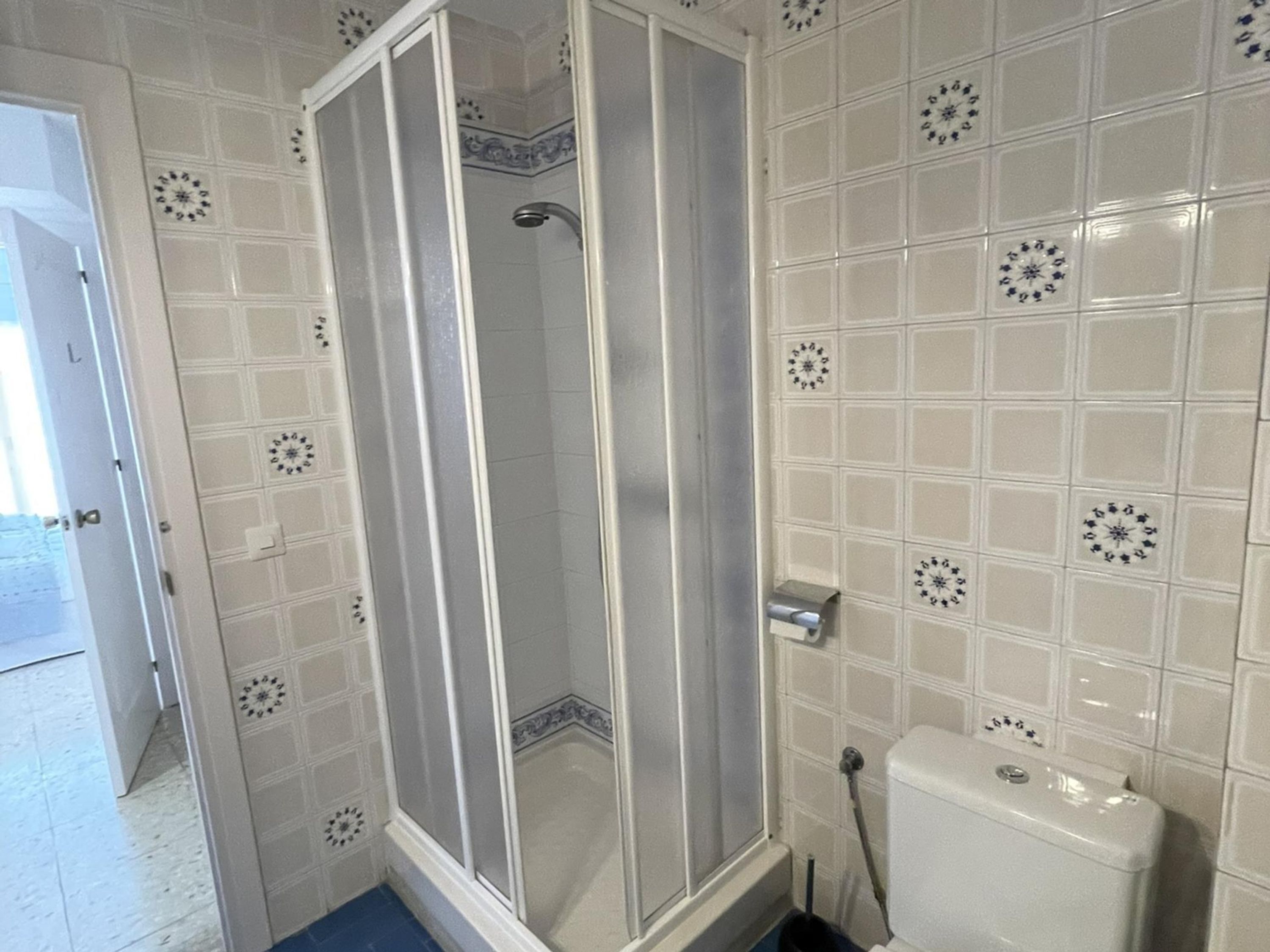 Een badkamer met een douchecabine, betegelde wanden en een toilet.