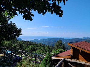 A wooden cabin with a red roof overlooking a mountainous landscape. - Villaggio Turistico Tecciù di Cuppi (Magliolo)