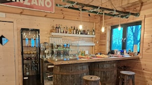 Un rústico espacio de bar con paredes de madera, una vitrina de vidrio y taburetes.